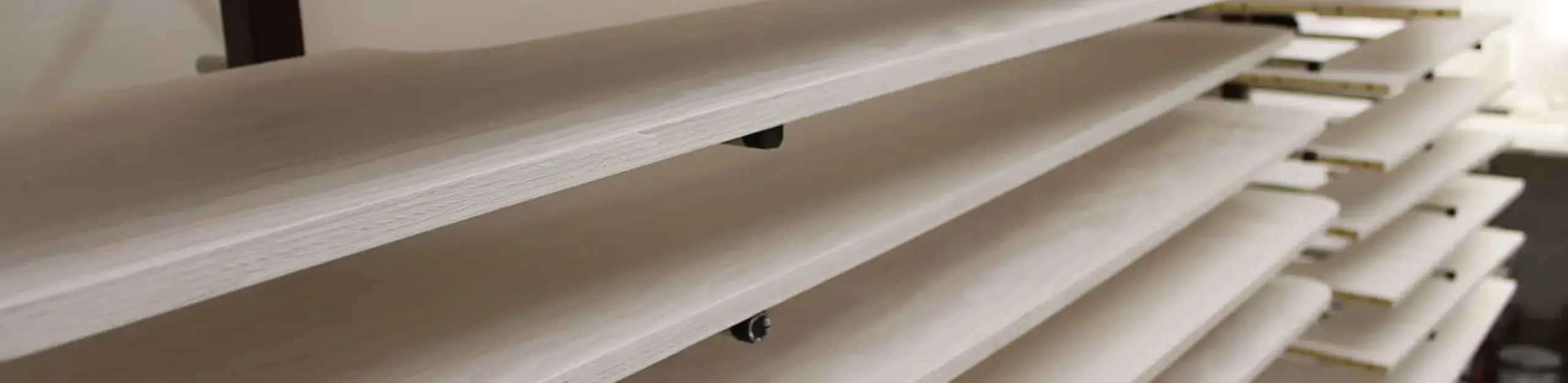 Éléments en bois peints en cours de séchage sur des racks