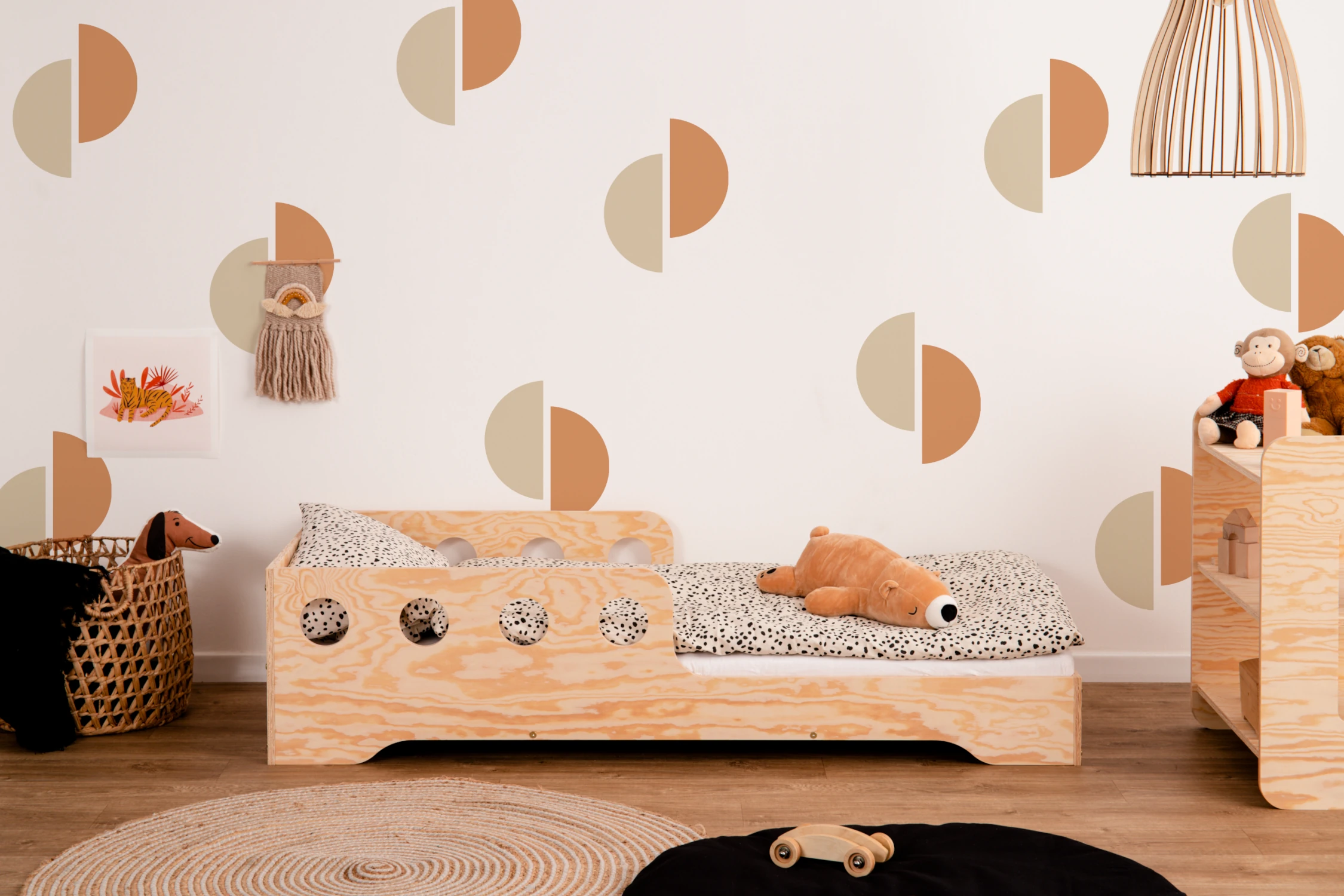 Lit en bois fabriqué en contreplaqué de pin couleur bois naturel avec une barrière à ouvertures rondes