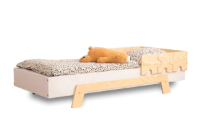 Lit en bois fabriqué en contreplaqué de pin avec une barrière en forme de puzzle en blanc