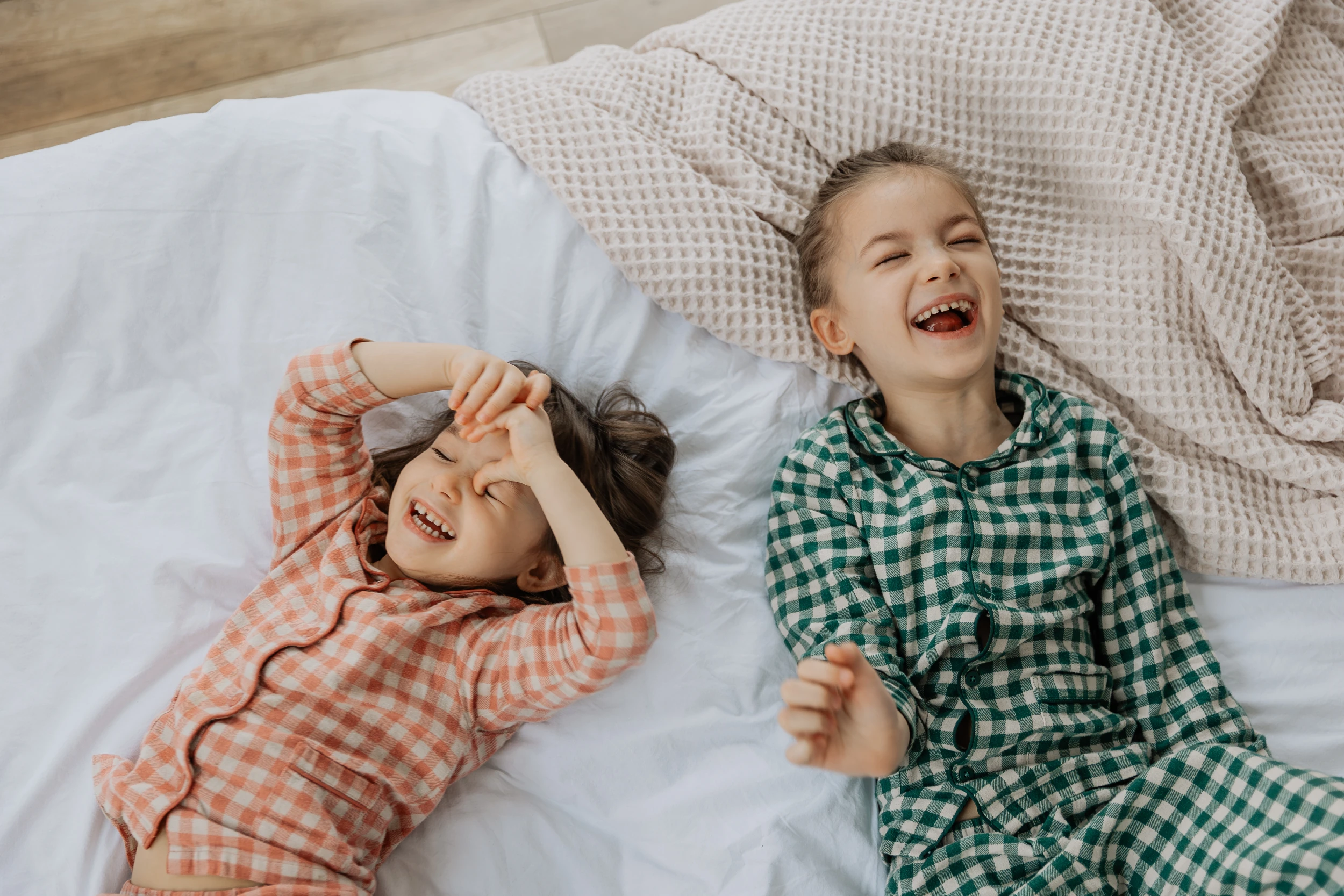 Deux enfants sur un lit avec draps blancs, moment de complicité